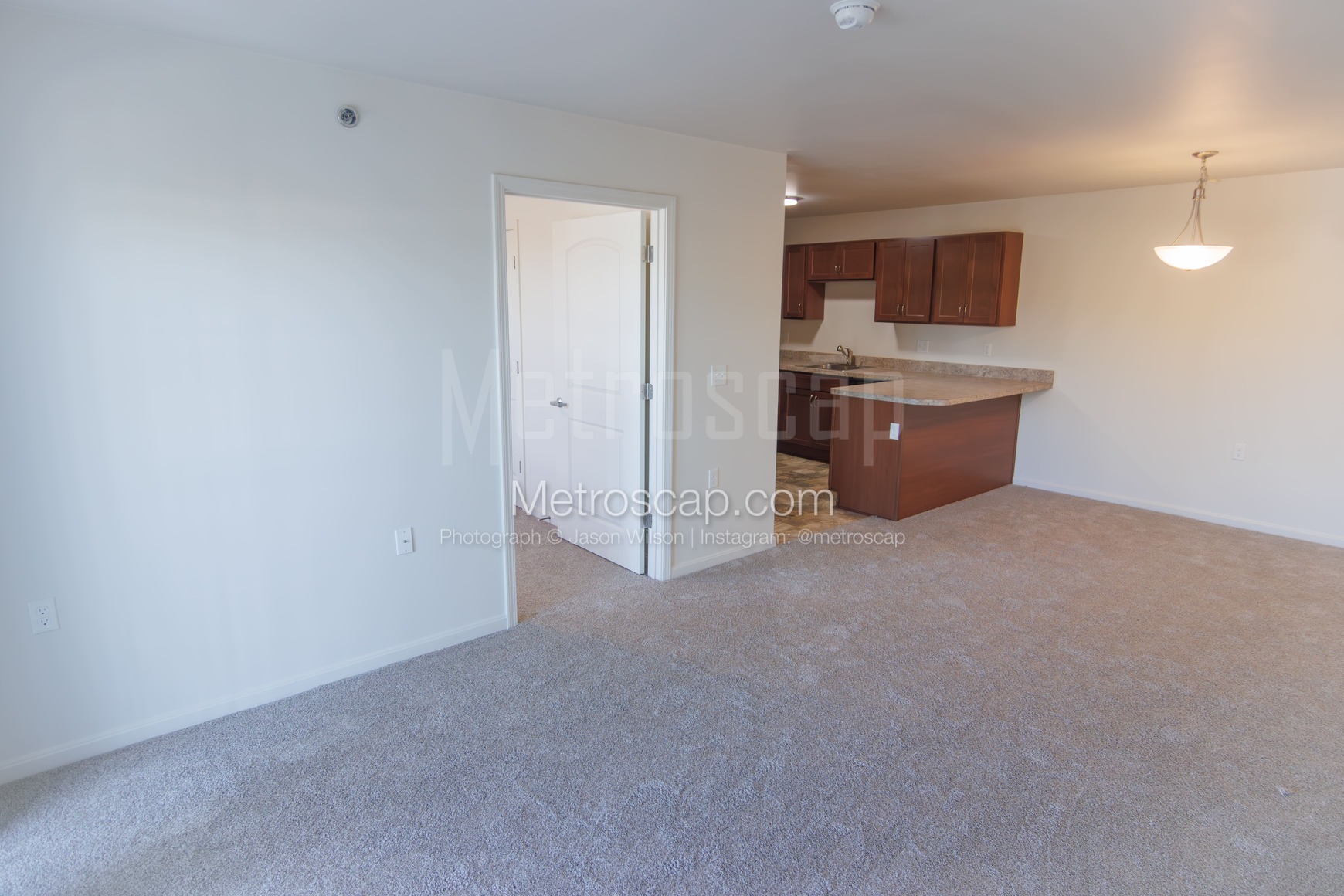 The interior of a vacant apartment showing the main living area and kitchen